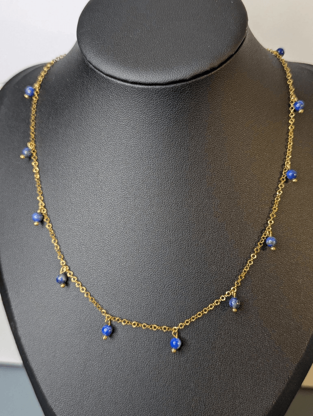 collier court avec une chaine en or fine et des perles naturelles de couleur bleu, la chaine fermoir est de couleur or. 