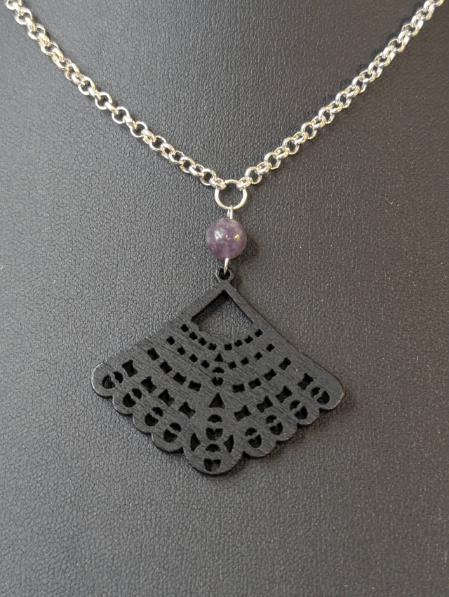 Collier court avec une chaine de couleur argent une perle naturelle et un pendentif en bois noir. 