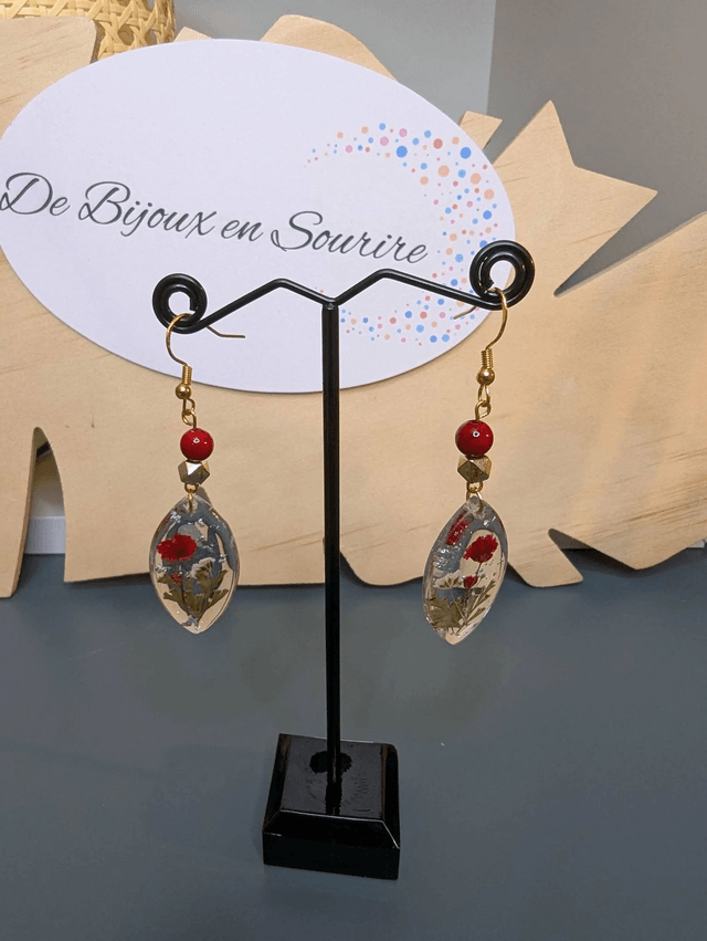 Boucles d'oreilles  avec un pendentif ovale en résine transparente et avec des fleurs séchés, des perle naturelle , le fermoir est en or.