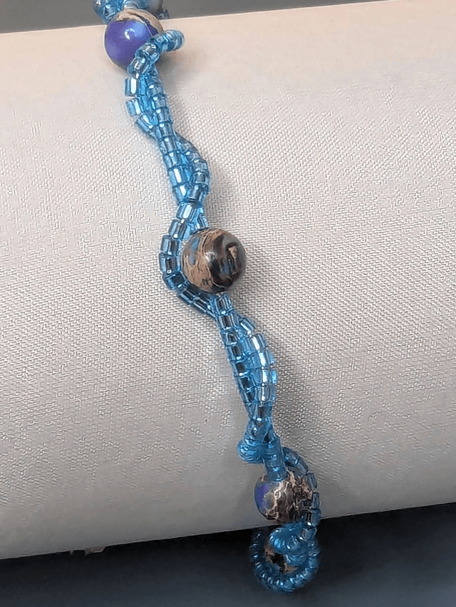 Bracelet torsadé bleu, avec des perles Miyuki en verre et des perles naturelles montées sur fil de fer. Le fermoir est de couleur argent.
