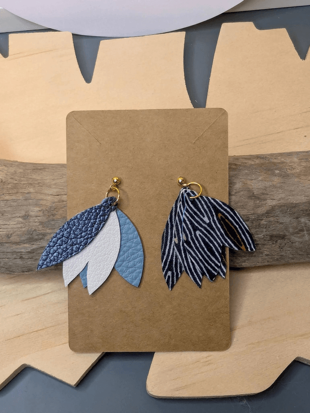 Boucles d'oreilles en cuir en forme de fleur de couleur bleu et blanc le derrière est en tissu enduit, le fermoir clou est en or.