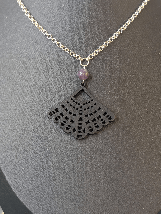 Collier court avec une chaine de couleur argent une perle naturelle et un pendentif en bois noir. 