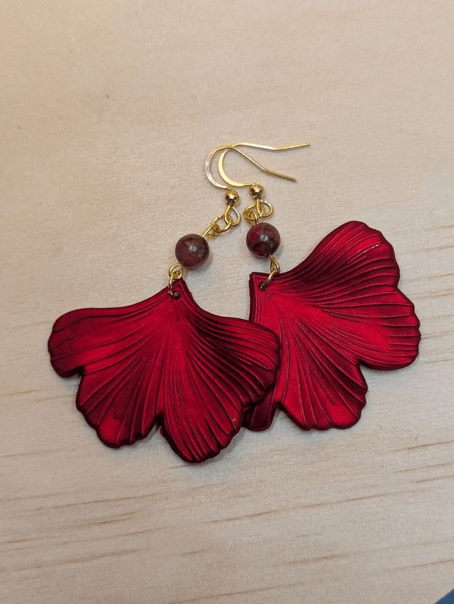Boucles d'oreilles avec pendentifs en forme de feuilles de couleur rouge métallisé avec des perles de cloisonne rouge et marron.