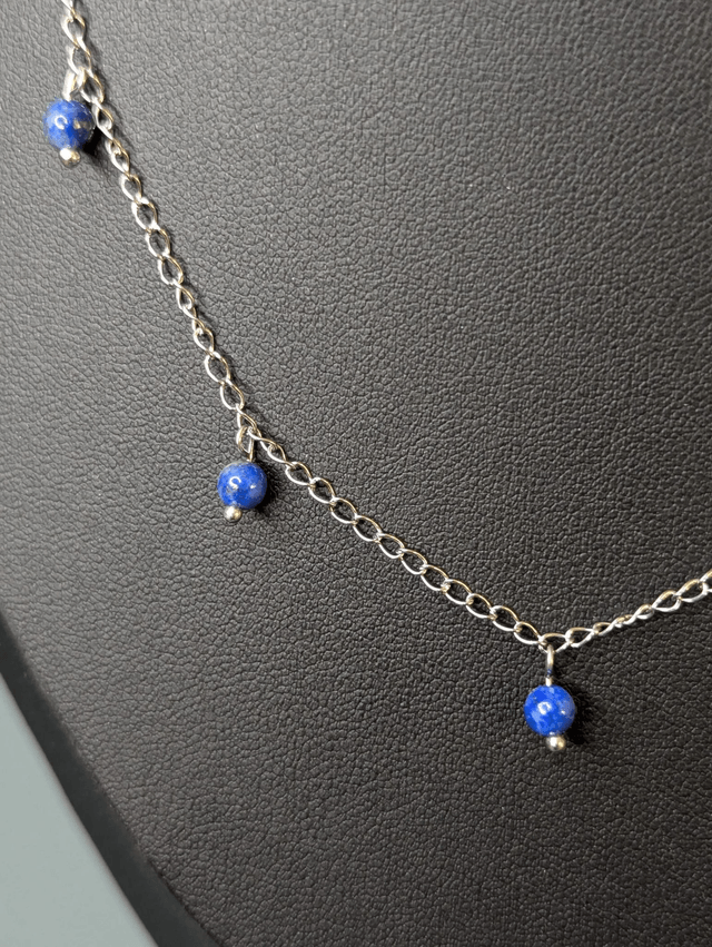 collier court chaine en argent fine et des perles naturelles de lapis lazuli de couleur bleu, la chaine fermoir est de couleur argent. 