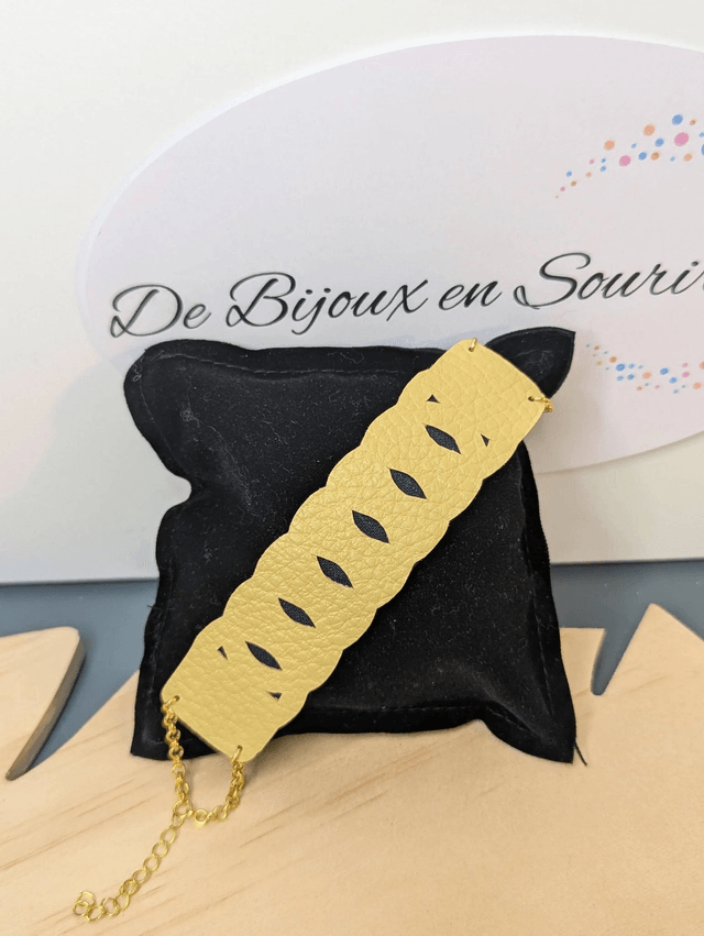 Bracelet manchette en cuir jaune, avec du tissus enduit bleu sombre (résistant), une chaine couleur or. Le fermoir est de couleur or.