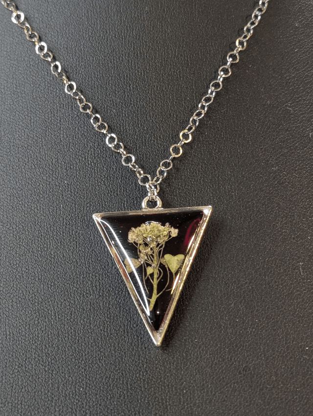 collier mi long de couleur argent avec un pendentif en résine rouge et fleur naturelle blanche. 