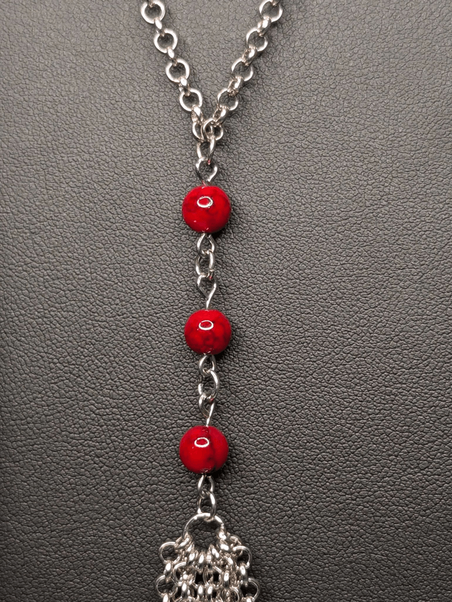 Collier long, sautoir, avec une chaine de couleur argent, des perles naturelles de turquoise rouge, et un pompon en chaine argentée. 
