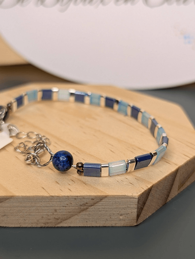 Bracelet en perles plate en verre bleu et perles d'espacement en métal argenté. Le fermoir et le chaine fermoir sont en argent.