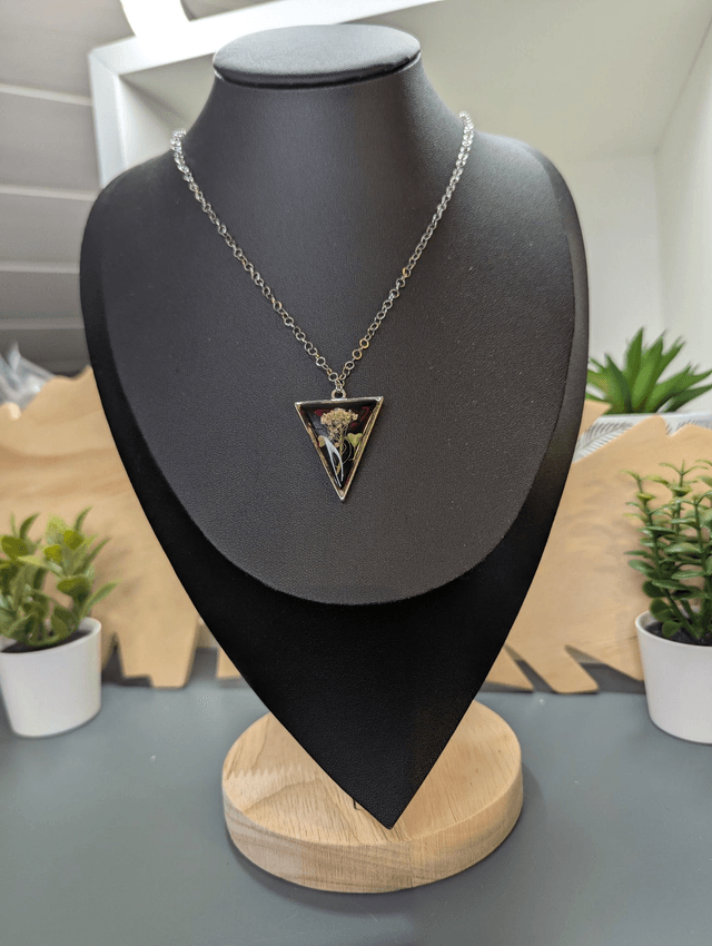 collier mi long de couleur argent avec un pendentif en résine rouge et fleur naturelle blanche. 