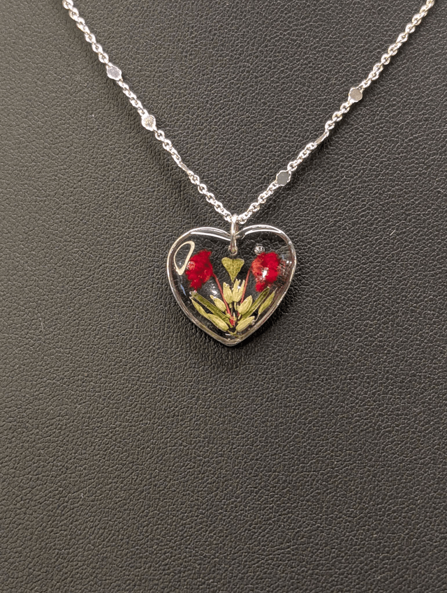 Collier avec une chaine de couleur argent et pendentif en résine en forme de cœur. 