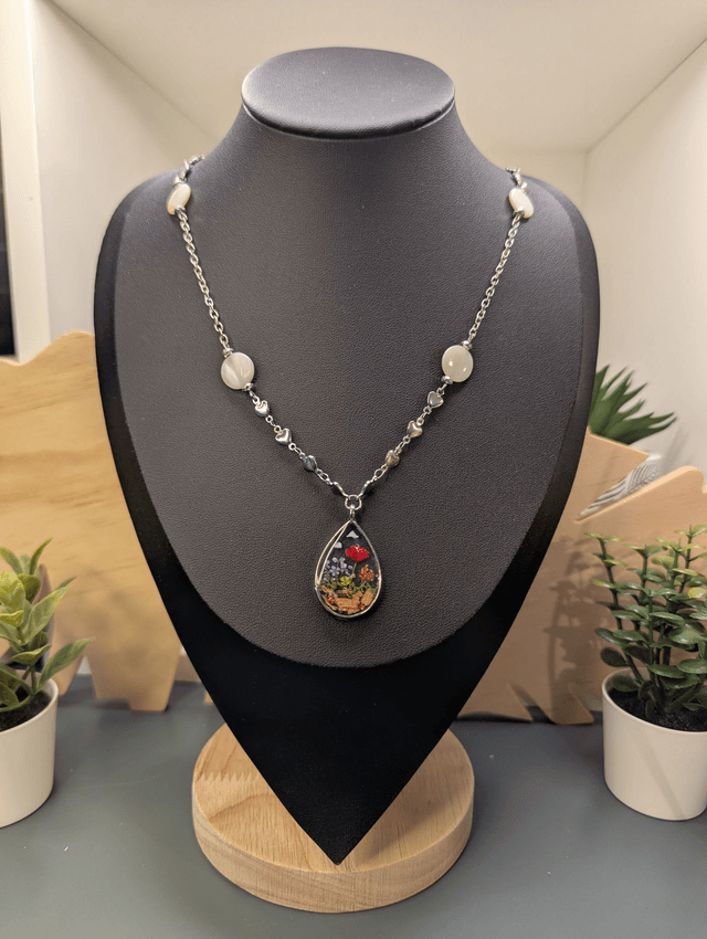 Collier mi long avec deux chaines de couleurs argent, des perles de nacre et un pendentif en résine avec fleurs séchés. 