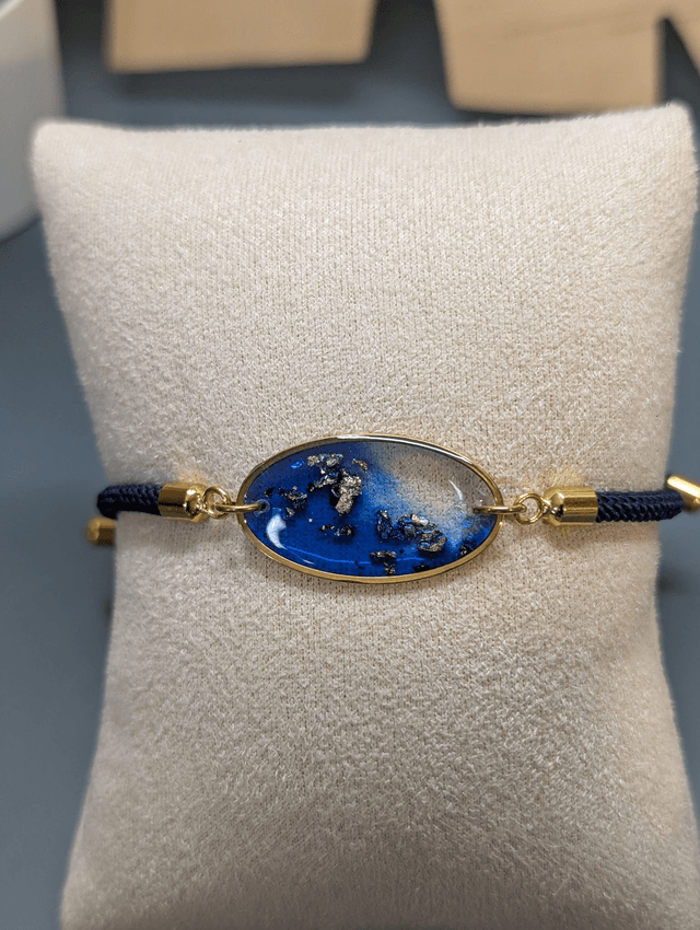 Bracelet corde ajustable bleu foncé et pendentif ovale en résine.