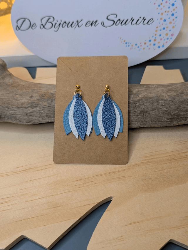 Boucles d'oreilles en cuir en forme de fleur de couleur bleu et blanc le derrière est en tissu enduit, le fermoir clou est en or.
