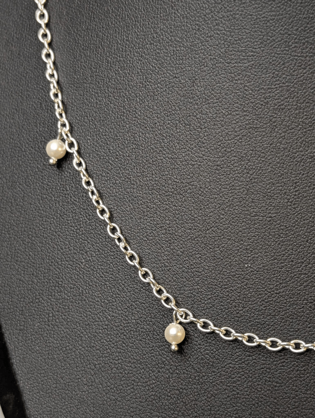 collier court avec une chaine en argent fine et des perles naturelles de coquillage blanc, la chaine fermoir est de couleur argenté. 