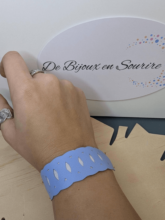 Bracelet manchette en cuir bleu lisse, avec du tissus enduit blanc (résistant), une chaine dorée. Le fermoir est de couleur or. 