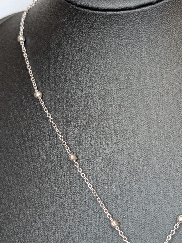 Collier mi long avec une chaine de couleur argent et un pendentif en résine noire avec des fleurs séchés. 