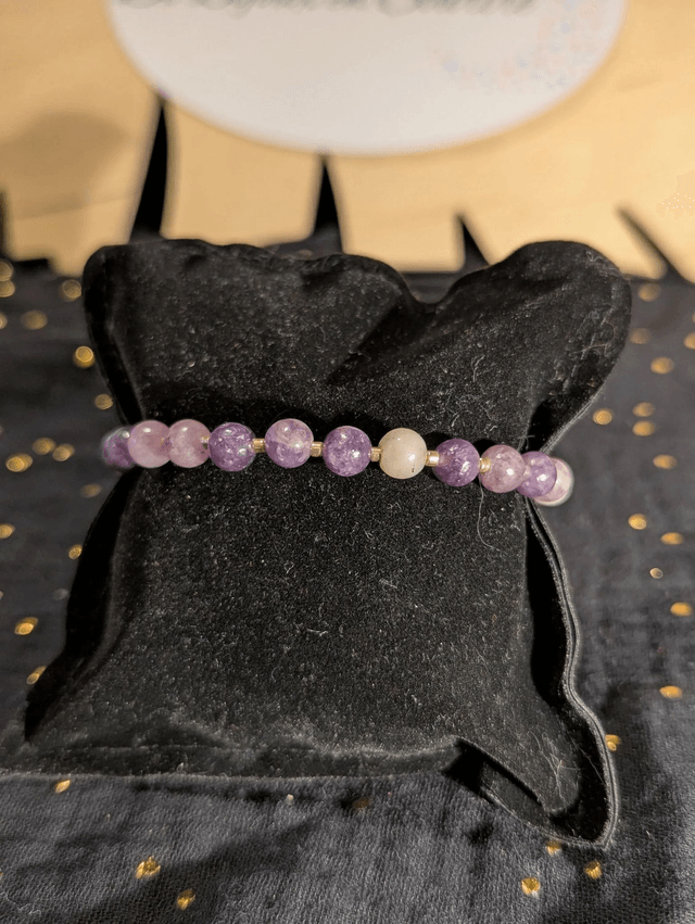 Bracelet en perles de lépidolite violette, et des perles d'espacement violette. Le fermoir et la chaine fermoir sont de couleur or.