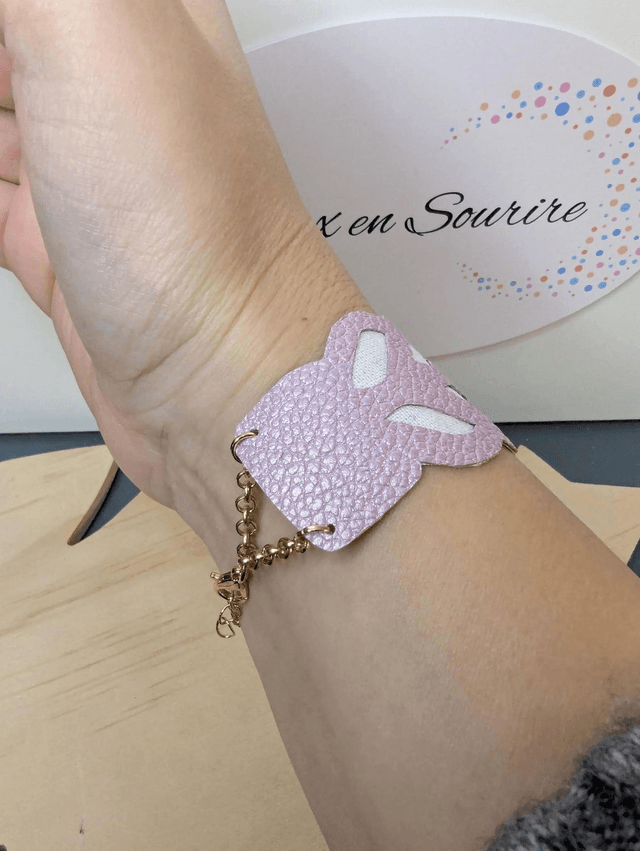 Bracelet manchette en cuir rose poudré, avec du tissus enduit blanc (résistant), une chaine couleur or. Le fermoir est de couleur or.