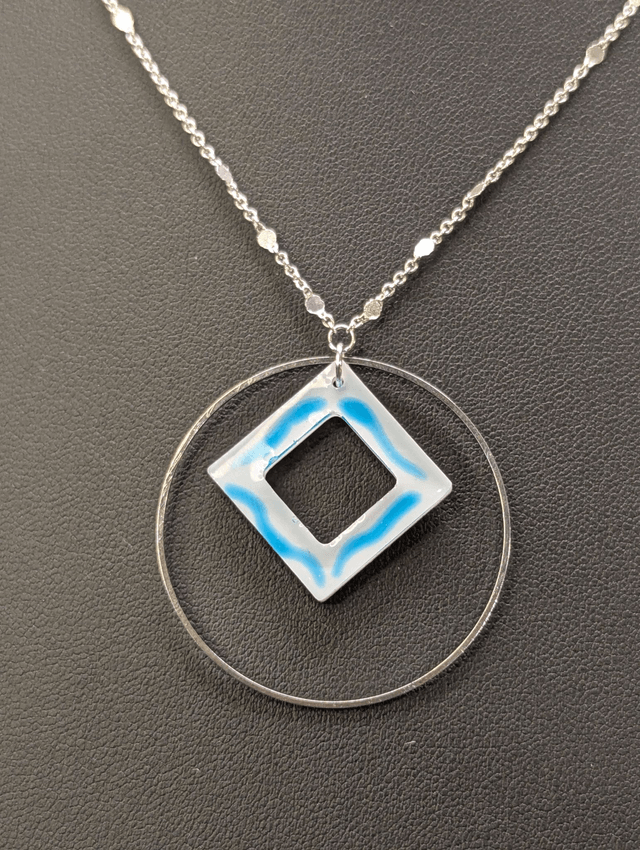 Collier court avec une chaine de couleur argent, un pendentif avec carré en résine et un cercle en métal argenté. 