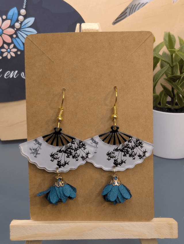 Boucles d'oreilles avec breloque éventail et pompon bleu.