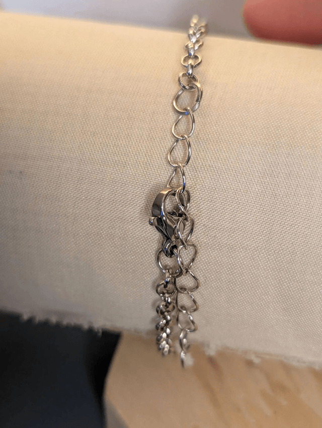  Bracelet avec une chaine de couleur argent et un pendentif en résine avec des fleurs séchés jaune, le fermoir est en argent. 