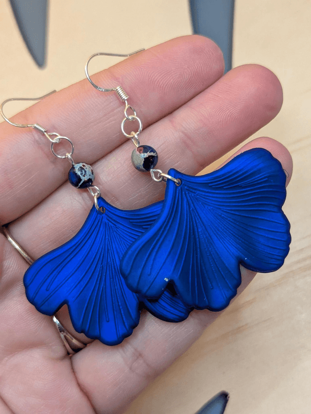 Boucles d'oreilles avec pendentifs en forme de feuilles de couleur bleu métallisé et des perles de jaspe sédiment de mer. 