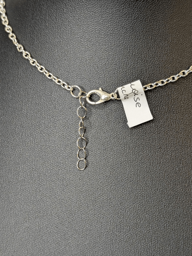 Collier mi long avec une chaine de couleur argent et un pendentif en résine bleu et blanc, et un pendentif en métal argenté. 