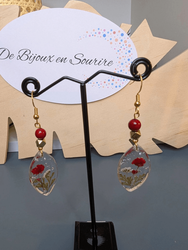 Boucles d'oreilles  avec un pendentif ovale en résine transparente et avec des fleurs séchés, des perle naturelle , le fermoir est en or.