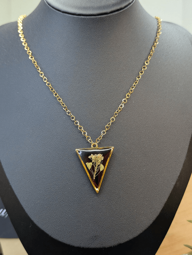 collier mi long de couleur or avec un pendentif en résine rouge et fleur naturelle blanche. 