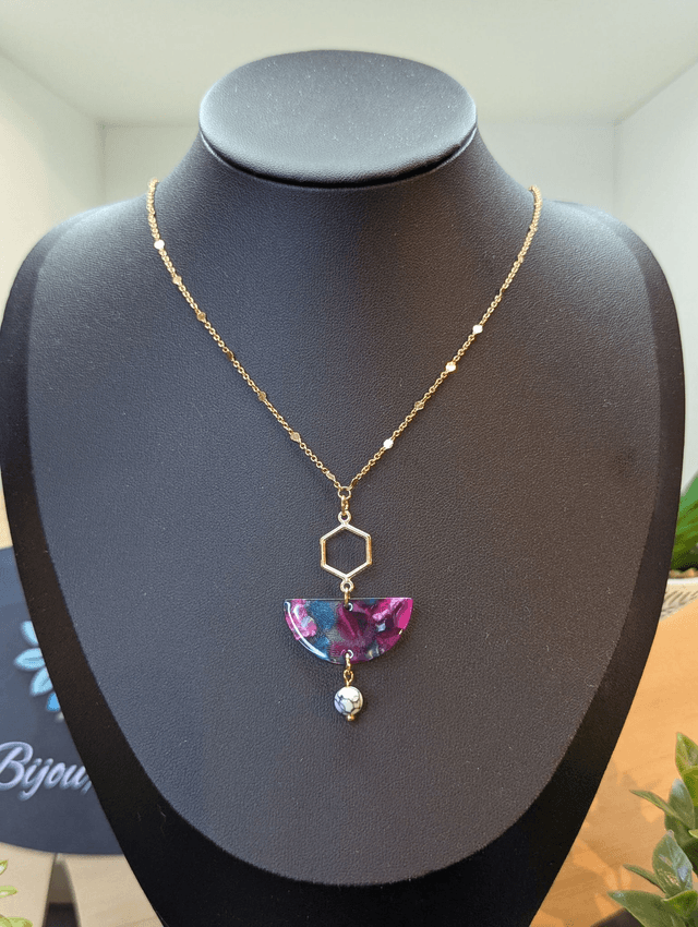 Collier mi long avec une chaine de couleur or et un pendentif en résine rose et bleu et un pendentif en métal doré.