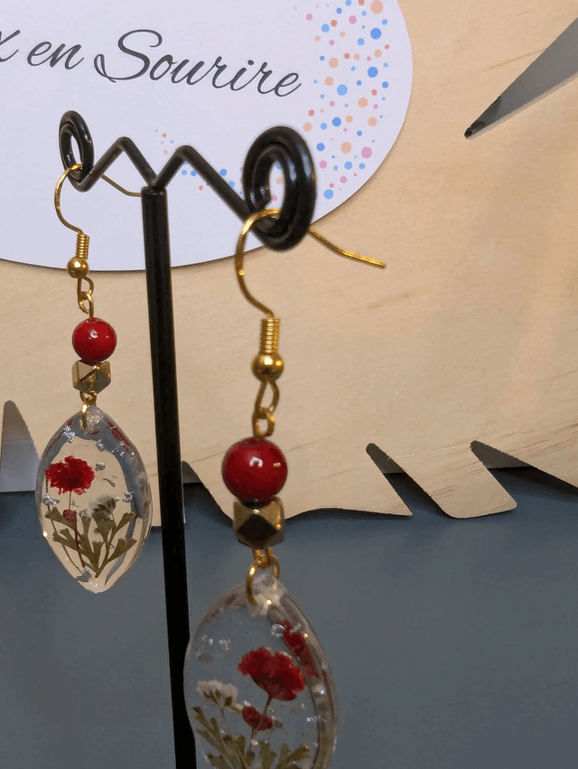 Boucles d'oreilles  avec un pendentif ovale en résine transparente et avec des fleurs séchés, des perle naturelle , le fermoir est en or.