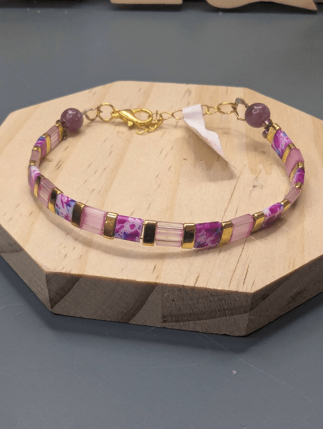 Bracelet avec des perles plate en verre rose et des perles d'espacement en métal doré. Le fermoir et la chaine fermoir sont en or.