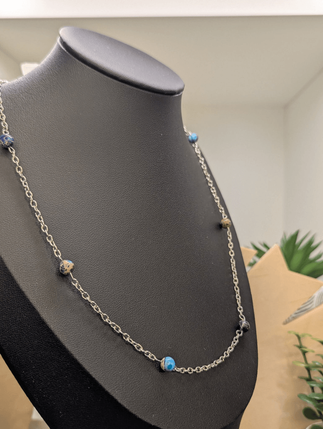 Collier mi-long avec une chaine fine en argent et des perles naturelles de jaspe de sédiment de mer. 