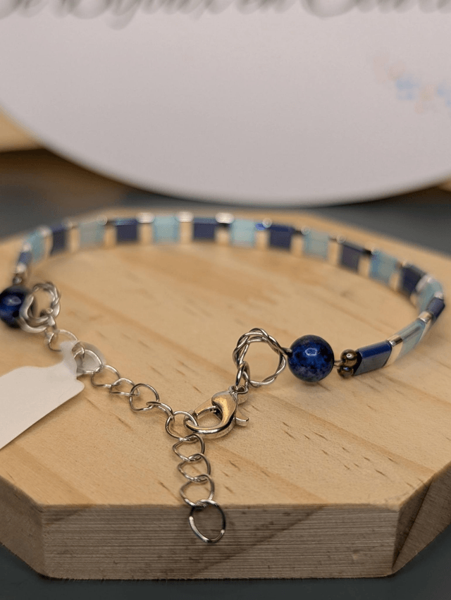 Bracelet en perles plate en verre bleu et perles d'espacement en métal argenté. Le fermoir et le chaine fermoir sont en argent.