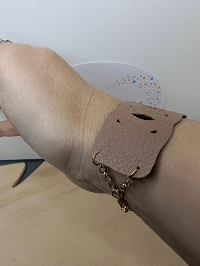 Bracelet manchette en cuir marron clair, avec du tissus enduit noir (résistant), une chaine dorée. Le fermoir est de couleur or.