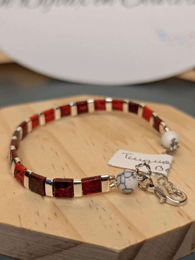 Bracelet en perles plate en verre rouge, perles d'espacement en métal argenté. le fermoir et la chaine fermoir sont en argent. 
