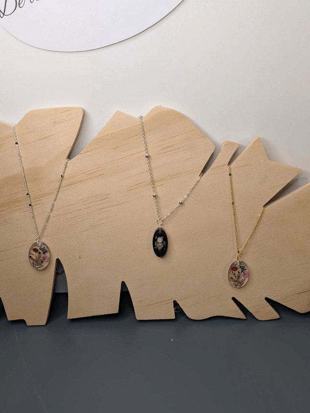 Collier mi long avec une chaine de couleur argent et un pendentif en résine avec des fleurs séchés rouge et rose. 