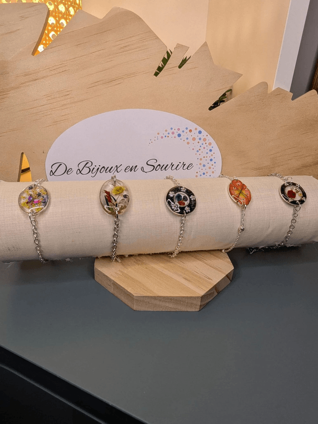 Bracelet avec une chaine de couleur argent, un pendentif en résine avec des fleurs séchés et un papillon en stickers, le fermoir est en argent. 