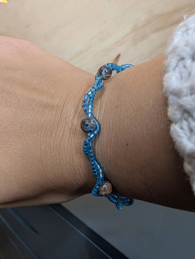 Bracelet torsadé bleu, avec des perles Miyuki en verre et des perles naturelles montées sur fil de fer. Le fermoir est de couleur argent.