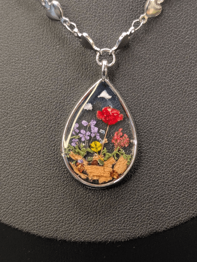 Collier mi long avec deux chaines de couleurs argent, des perles de nacre et un pendentif en résine avec fleurs séchés. 