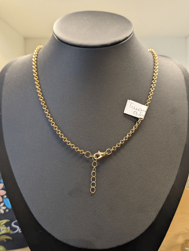 Collier mi long avec une chaine de couleur or et un pendentif en résine bleu et blanc et un pendentif en métal doré.