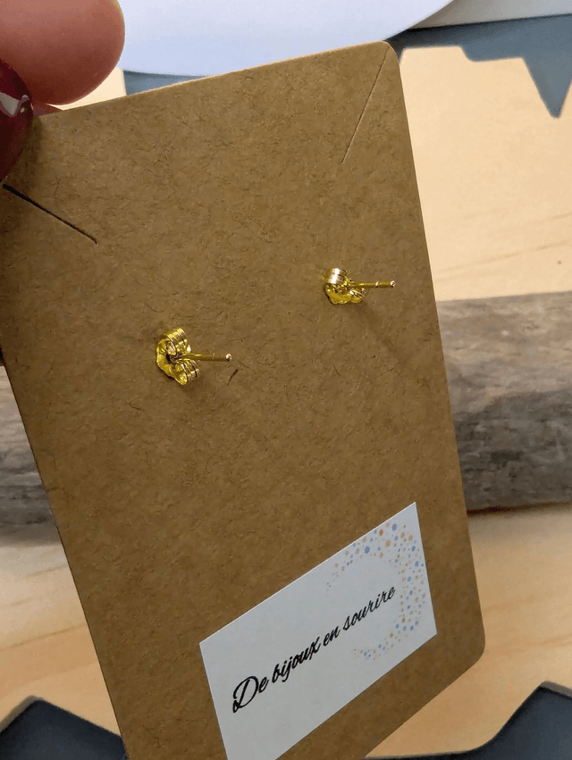 Boucles d'oreilles en cuir en forme de fleur de couleur bleu et blanc le derrière est en tissu enduit, le fermoir clou est en or.