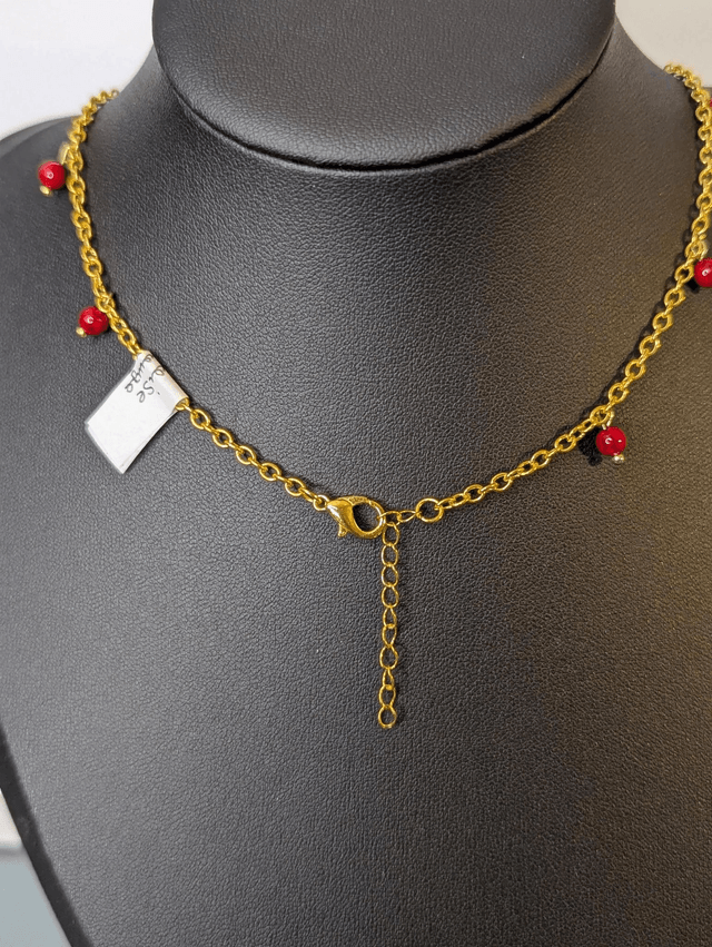collier court chaine en or fine et des perles naturelles de couleur rouge, la chaine fermoir est de couleur or. 