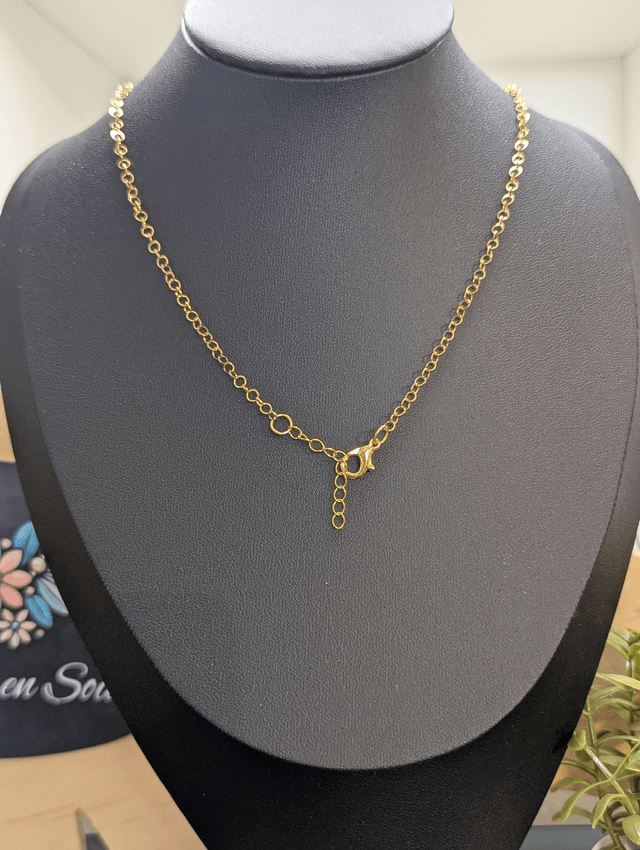 collier mi long avec chaine de couleur or et pendentif en verre de couleur bleu foncé.