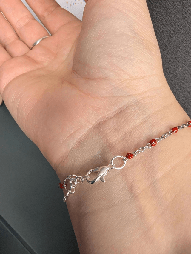 Bracelet en chaine de couleur argent et cœur en cuir et tissus enduit rouge, le fermoir est de couleur argent. 