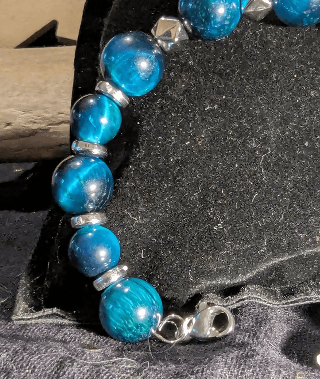 Bracelet en perles d'œil de tigre bleu et des perles d'espacement plate en argent. Le fermoir et la chaine fermoir sont en argent.