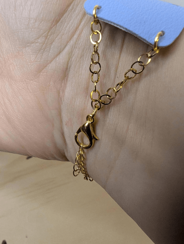 Bracelet manchette en cuir bleu lisse, avec du tissus enduit blanc (résistant), une chaine dorée. Le fermoir est de couleur or. 
