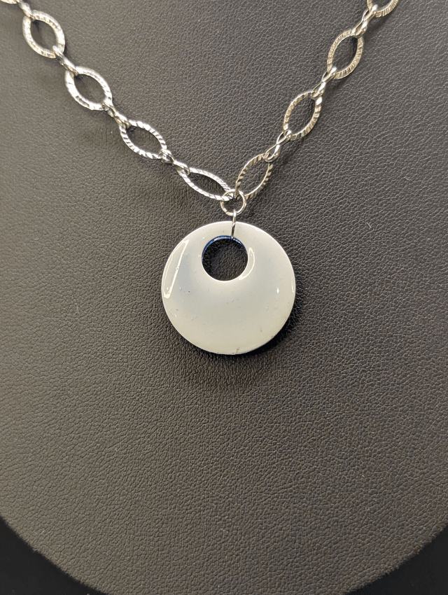 Collier avec une chaine de couleur argent et un pendentif rond  en résine bleu. 