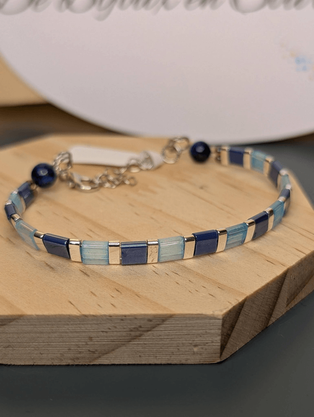 Bracelet en perles plate en verre bleu et perles d'espacement en métal argenté. Le fermoir et le chaine fermoir sont en argent.