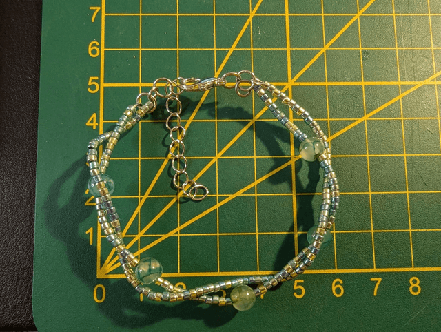 Bracelet torsadé vert avec des perles de  Miyuki en verre et des perles naturelles, montées sur fil de fer. Le fermoir est en couleur argenté.